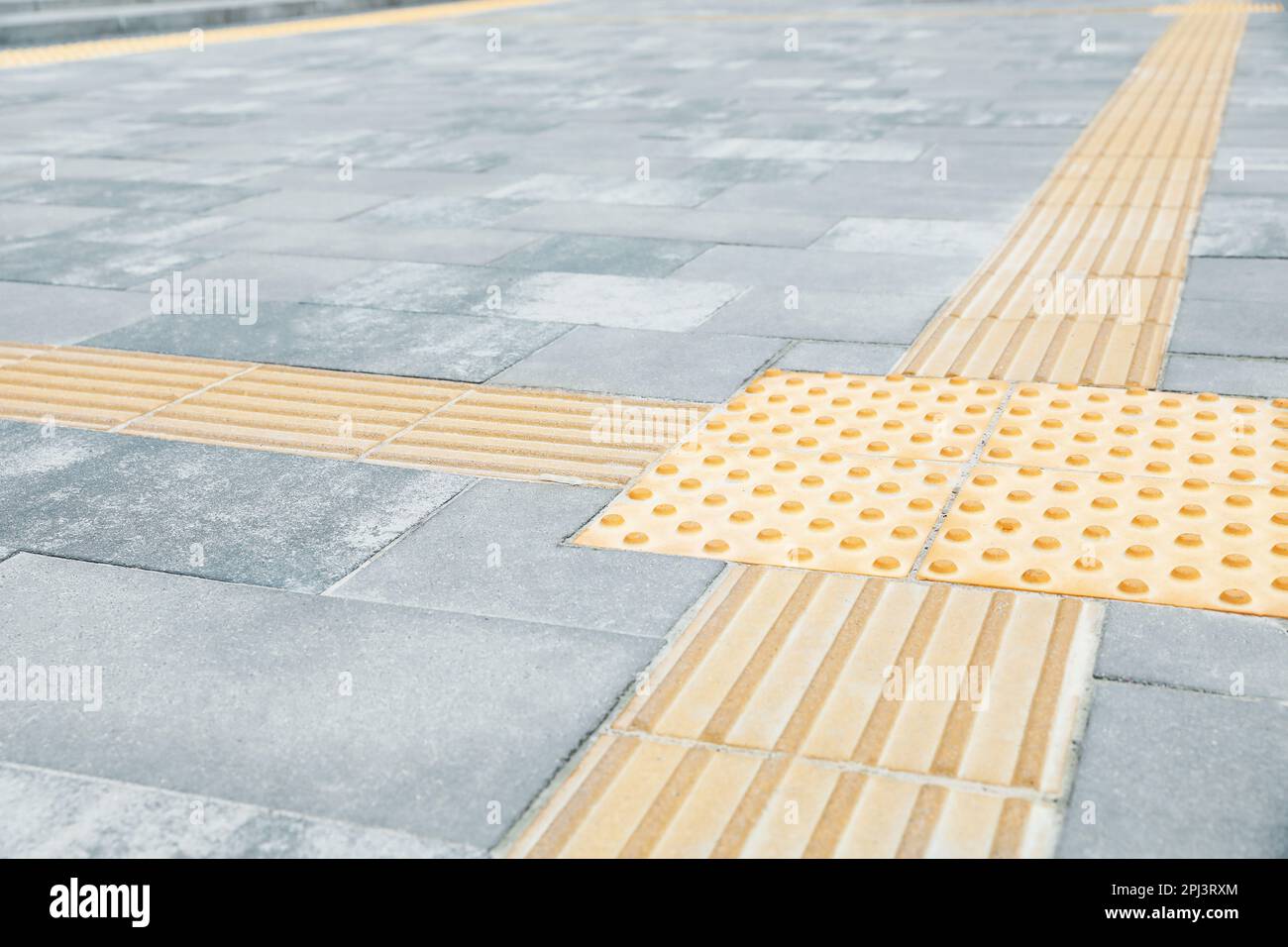 Grey pavement with tactile tiles outdoors. Public environment
