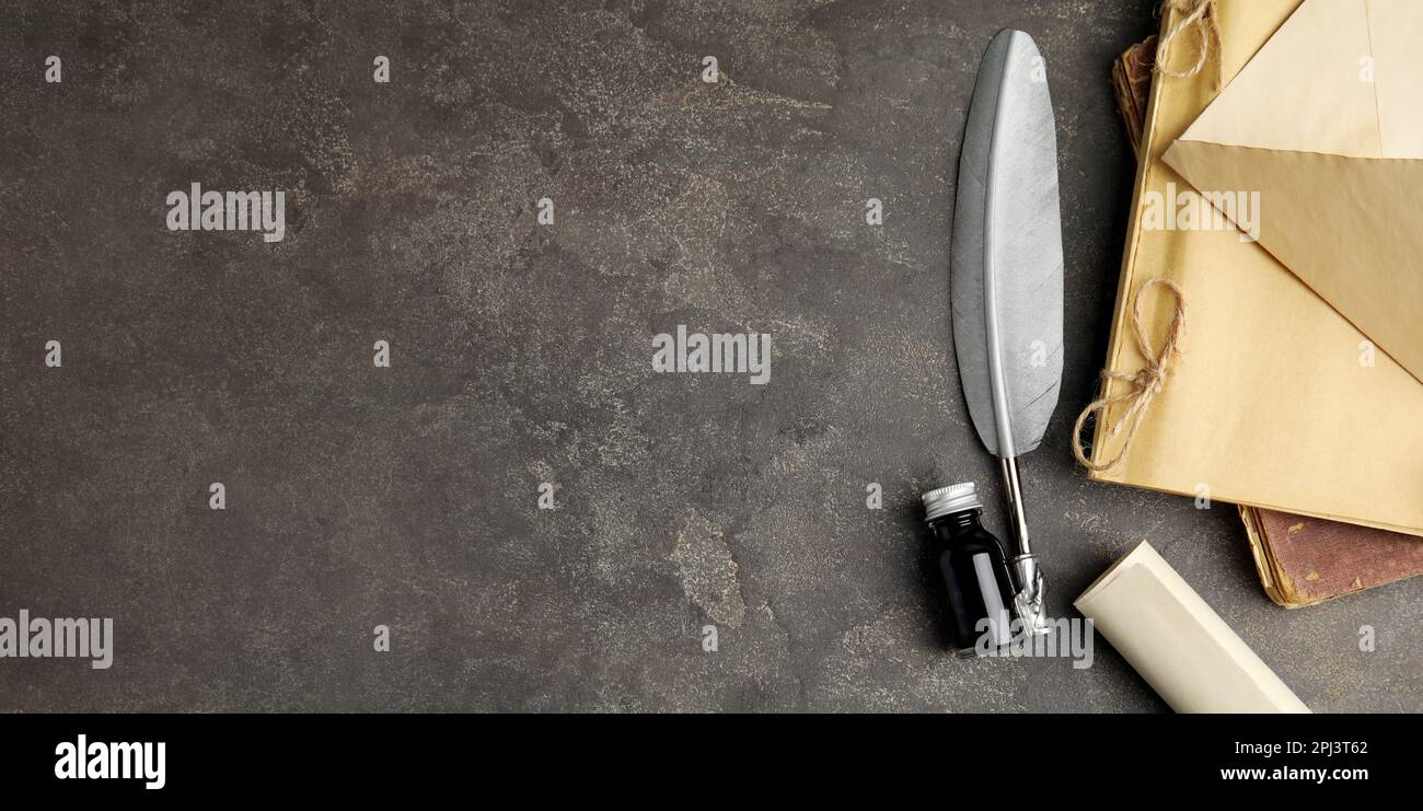 Flat lay composition with quill and bottle of ink on grey table, space ...