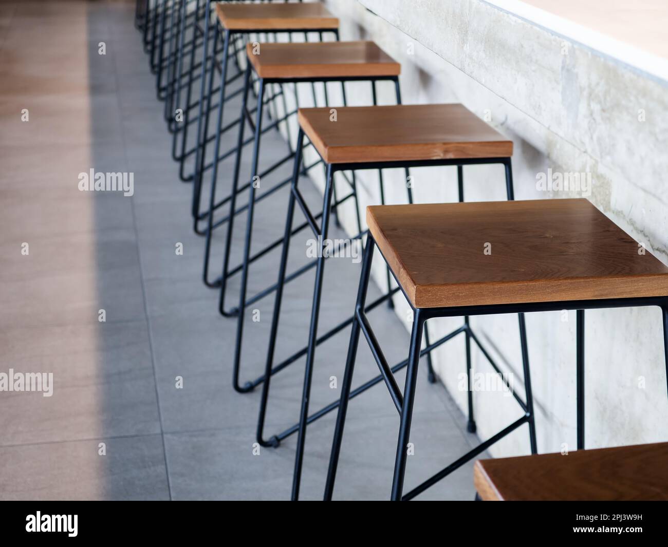 Row of wooden bar stool chairs beside concrete counter bar, loft style