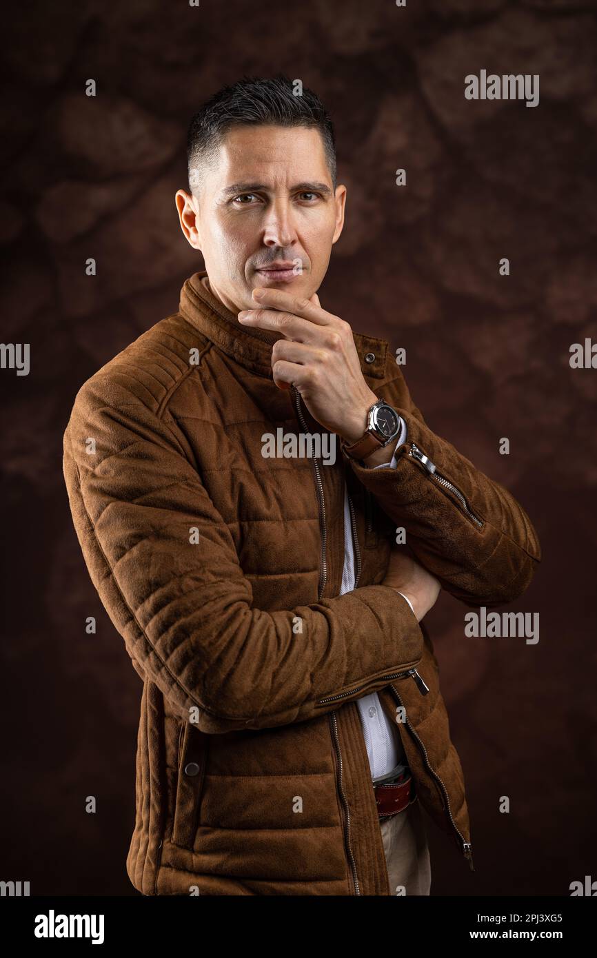 Man with serious expression posing in studio against brown background Stock Photo
