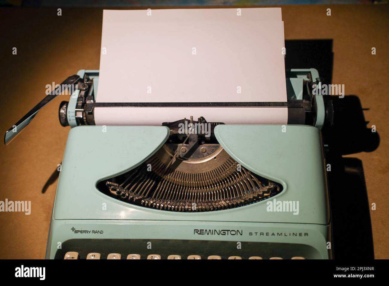 Old green typewriter Remington in light with blank page in the