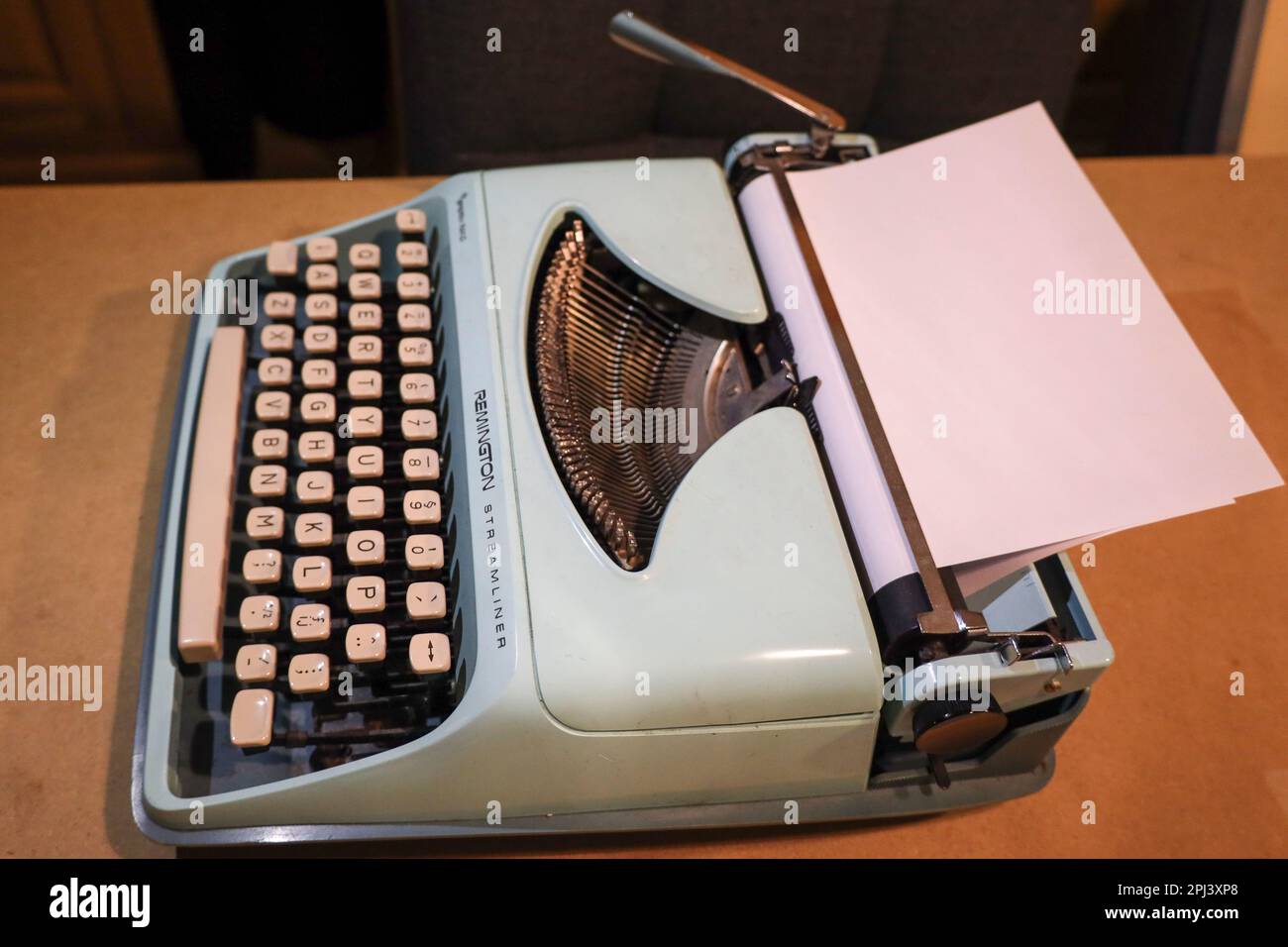Old green typewriter Remington in light with blank page in the