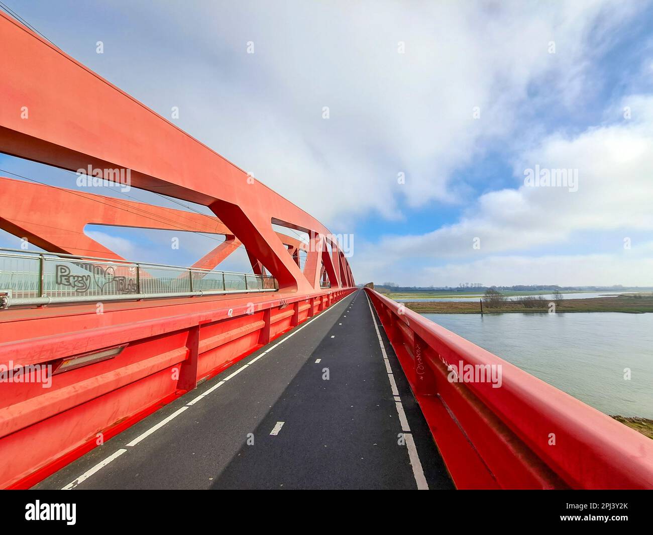 Red steel bridge called Hanzeboog over the river IJssel between Hattem