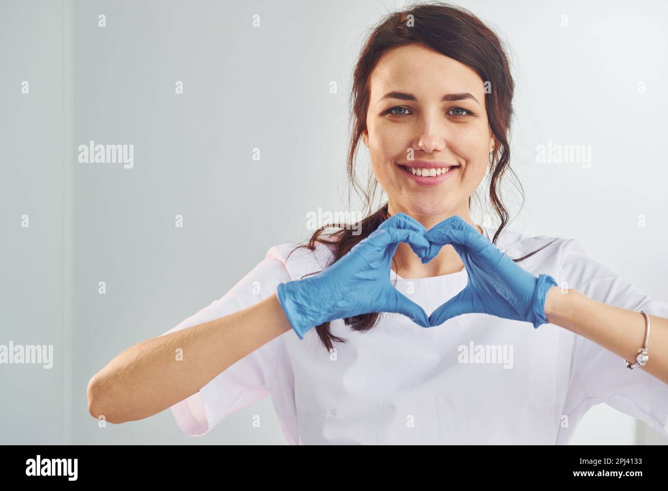 Heart shaped gesture. Portrait of professional female dentist with equipment that standing