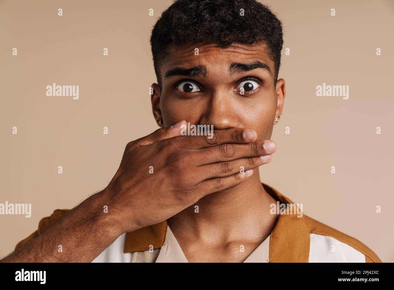 Shocked black man covering his mouth and looking at camera isolated ...