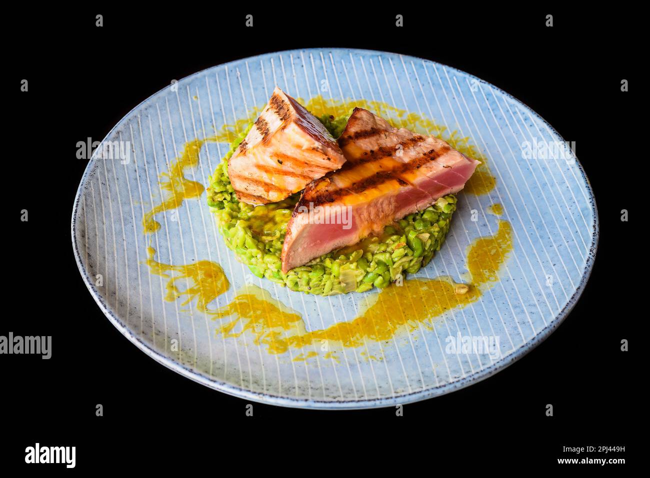 Tuna steak medium rare served with peas isolated on black background