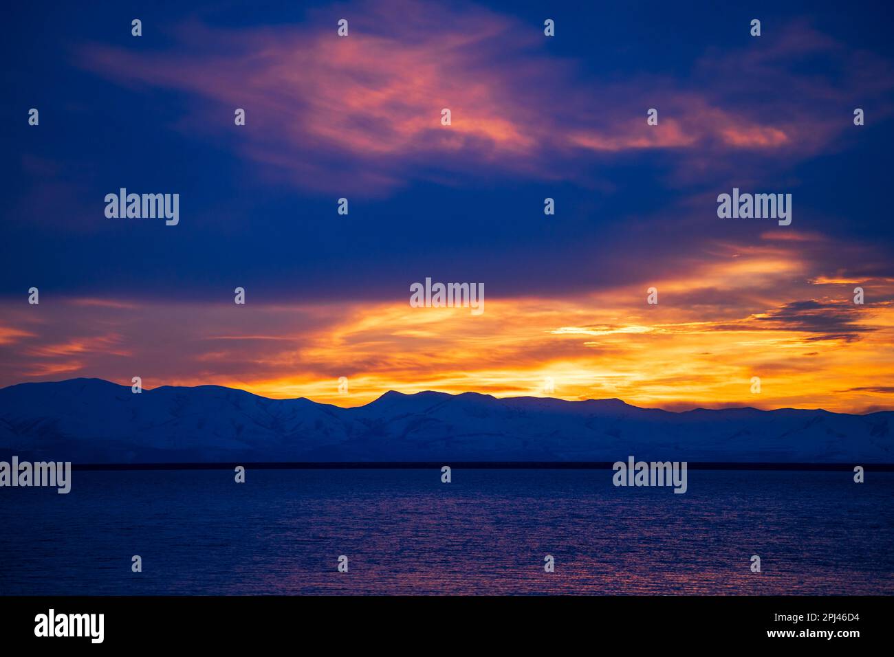 The sun sets over the snow-covered Promontory Mountains and reflects on the waters of Willard Bay Reservoir, Willard, Box Elder County, Utah, USA. Stock Photo