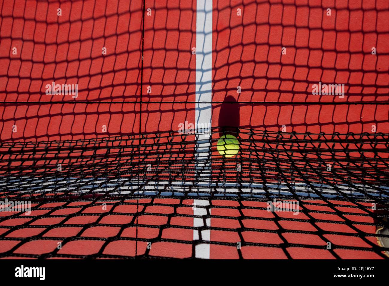 selective focus, a ball on the net of a red tennis court Stock Photo