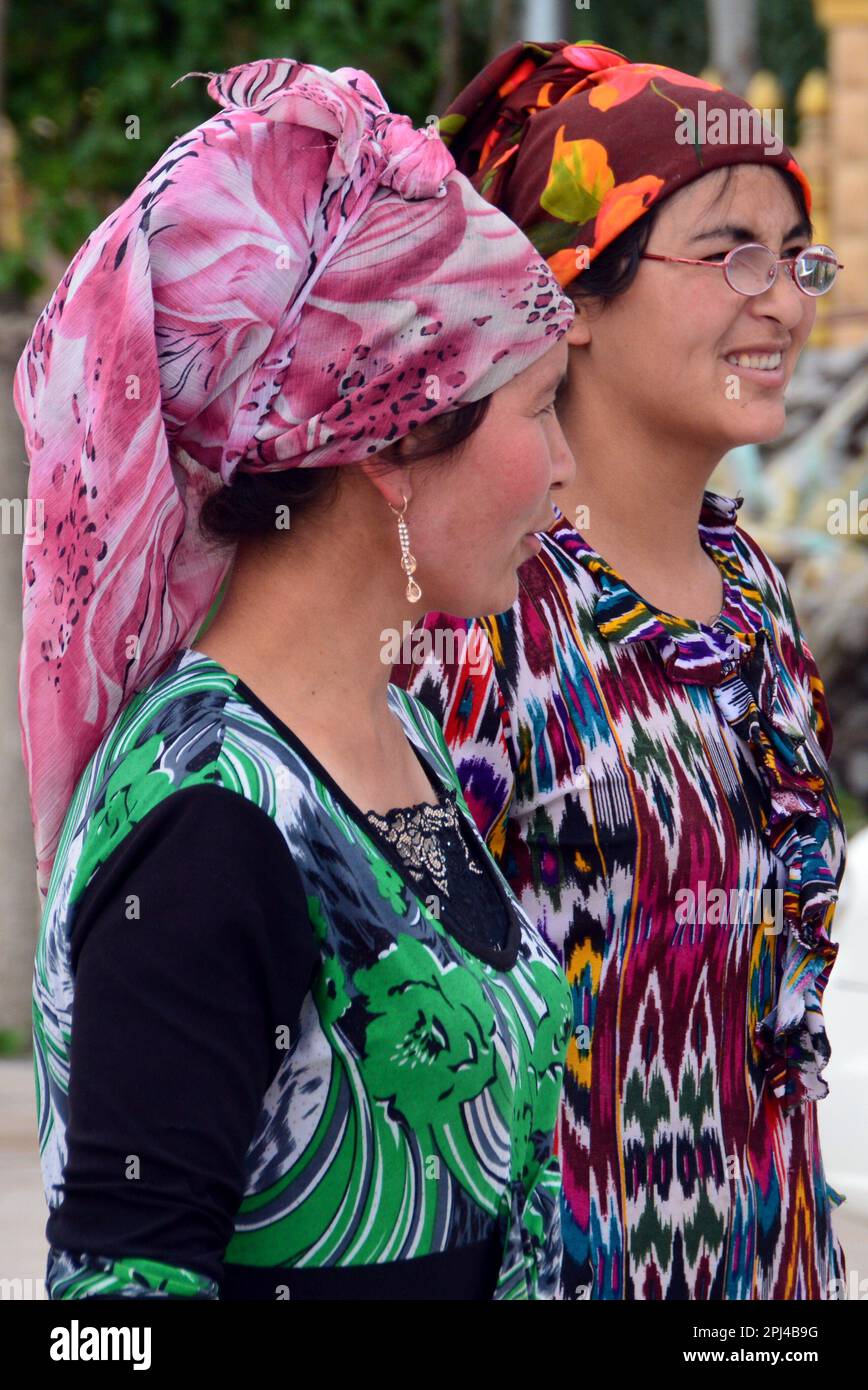 People's Republic of China,  Xinjiang Province, Kashgar, the Sunday Market:  two Uighur women wearing typical brightly-coloured dresses. Stock Photo