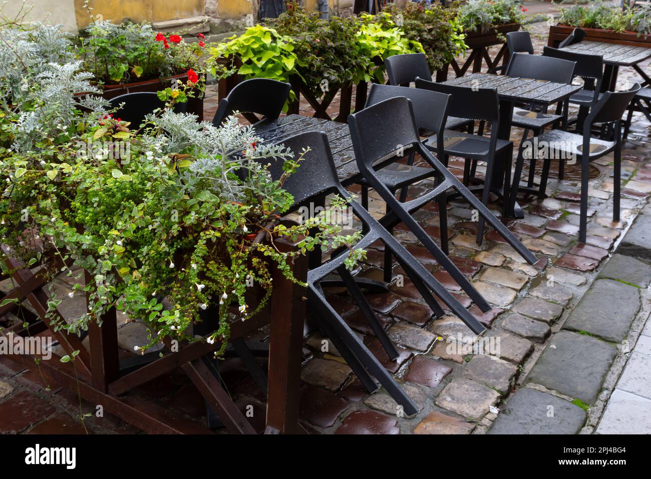 Empty wet wooden table and chairs on terrace of outdoor cafeteria
