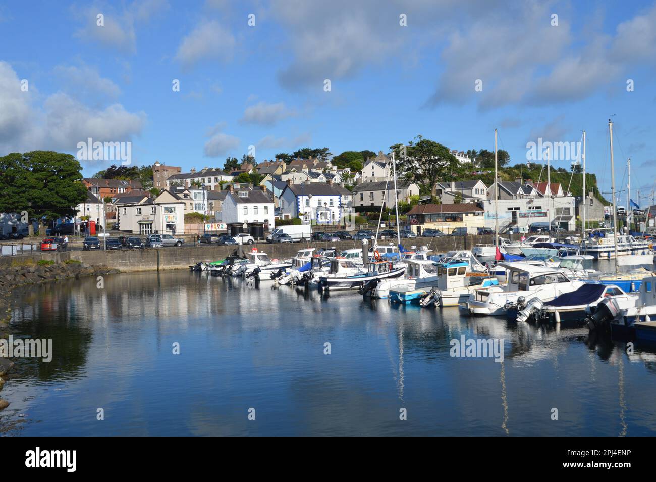 Northern Ireland, County Antrim, Ballycastle:  fishing boats reflected in the waters of the harbour, overlooked by the rising ground of the town. Stock Photo
