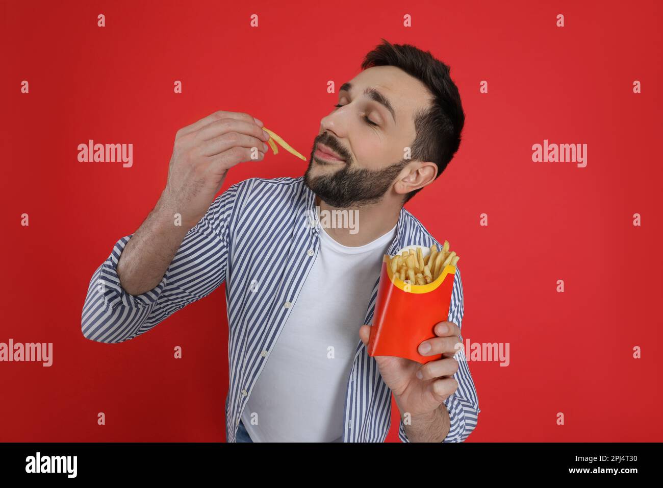 Man eating French fries on red background Stock Photo