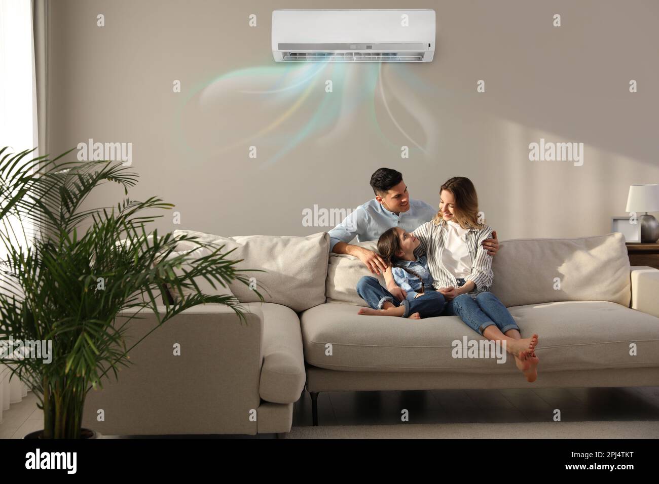Happy family resting under air conditioner on beige wall at home Stock Photo Alamy