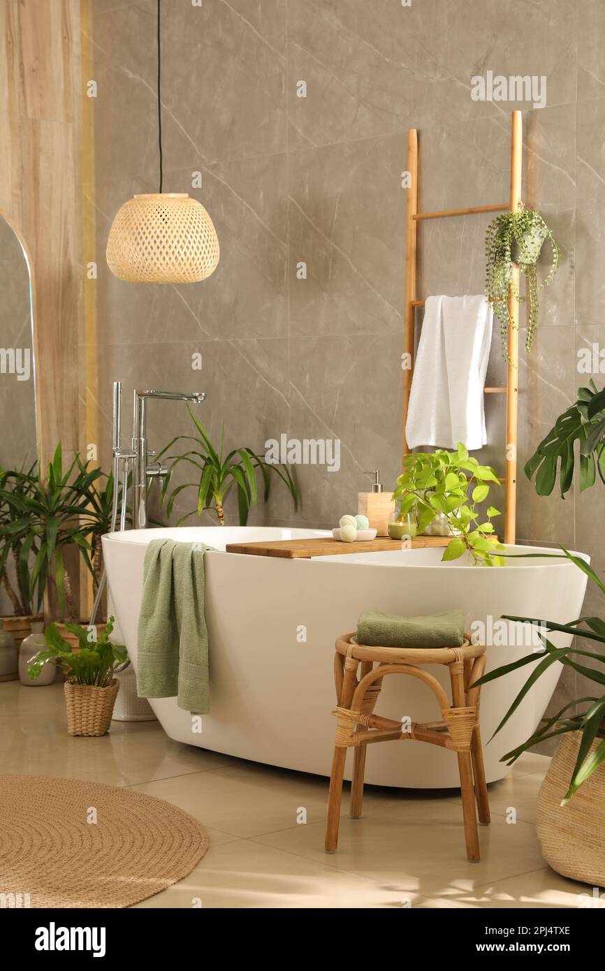 Modern white tub and beautiful green houseplants in bathroom. Interior ...