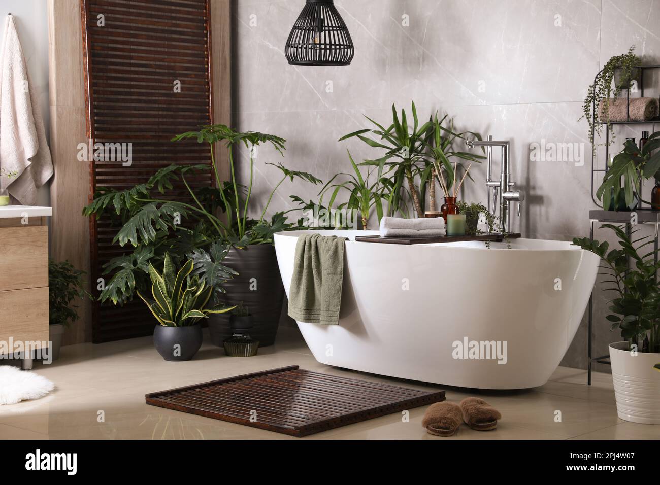 Modern white tub and beautiful green houseplants in bathroom. Interior ...
