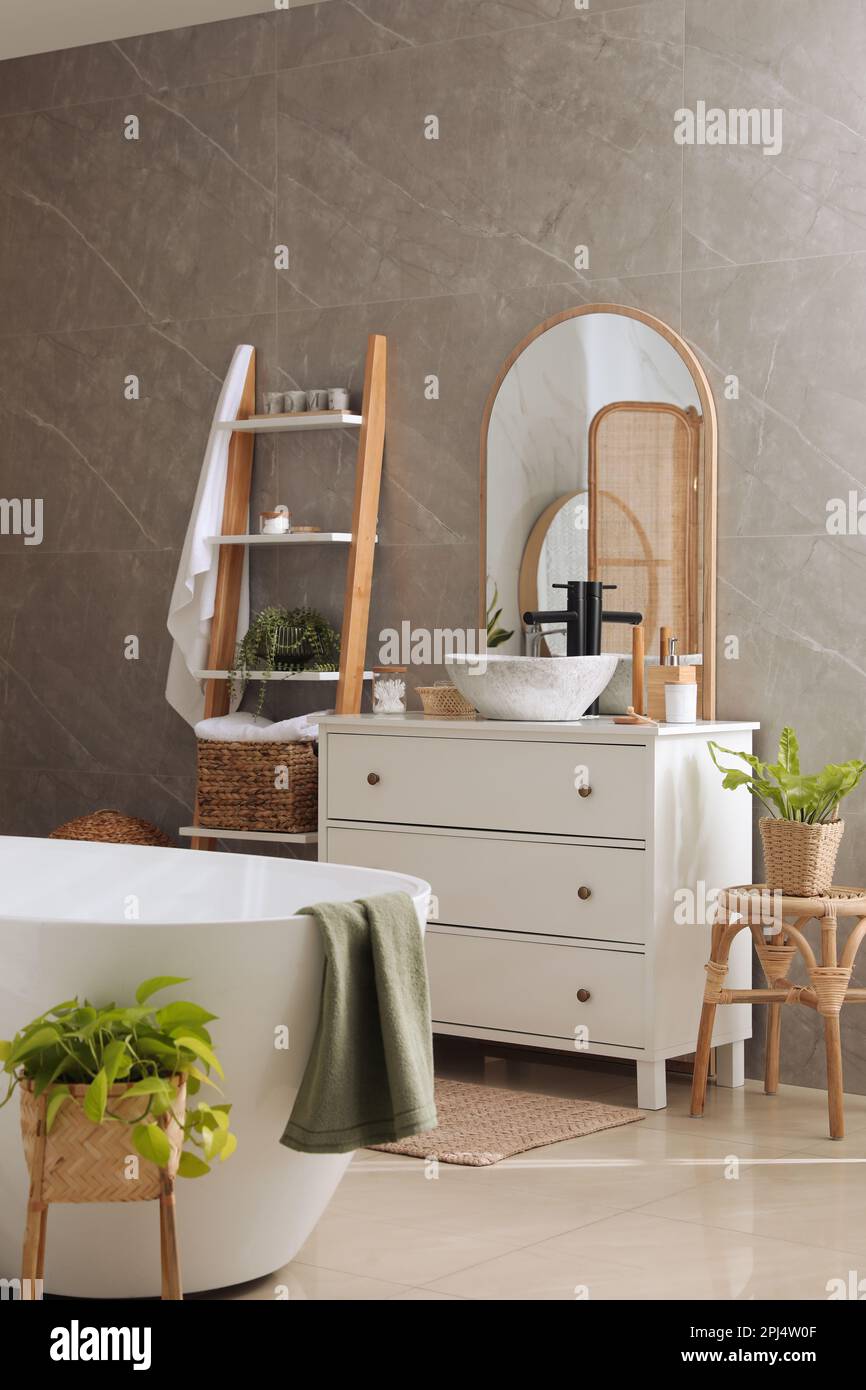 Modern white tub and chest of drawers with sink in bathroom. Interior