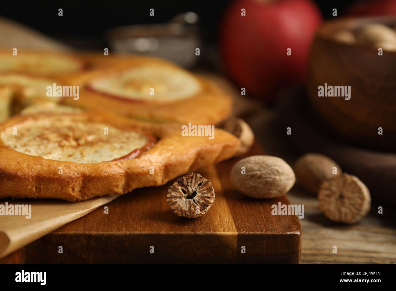 Nutmeg seeds and tasty apple pie on wooden table, closeup Stock Photo