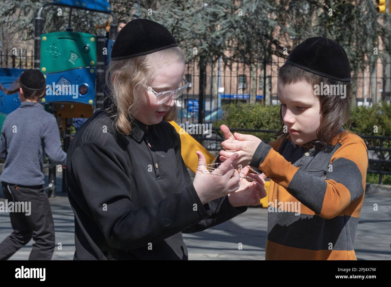 During recess, 2 orthodox Jewish students with long peyes play Cat's Cradle, a game palyed with string. In Brooklyn, New York. Stock Photo
