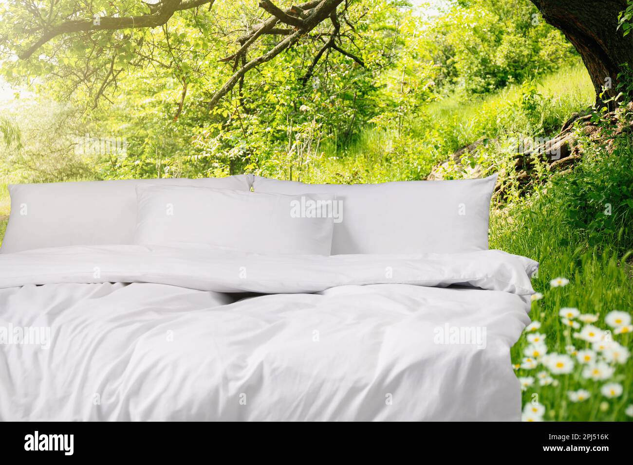 Comfortable bed with soft pillows outdoors on sunny day Stock Photo