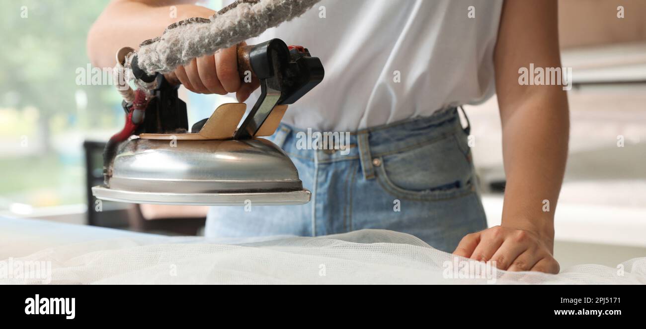 Closeup view of female worker ironing laundry, banner design. Dry