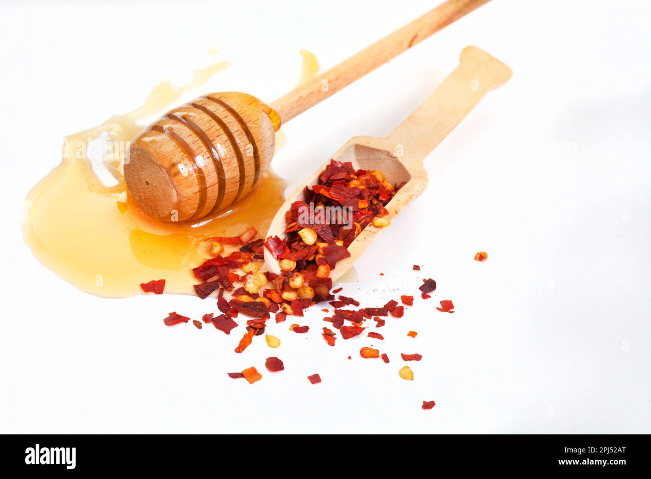 Hot honey or chili honey on white with loose chili flakes Stock Photo