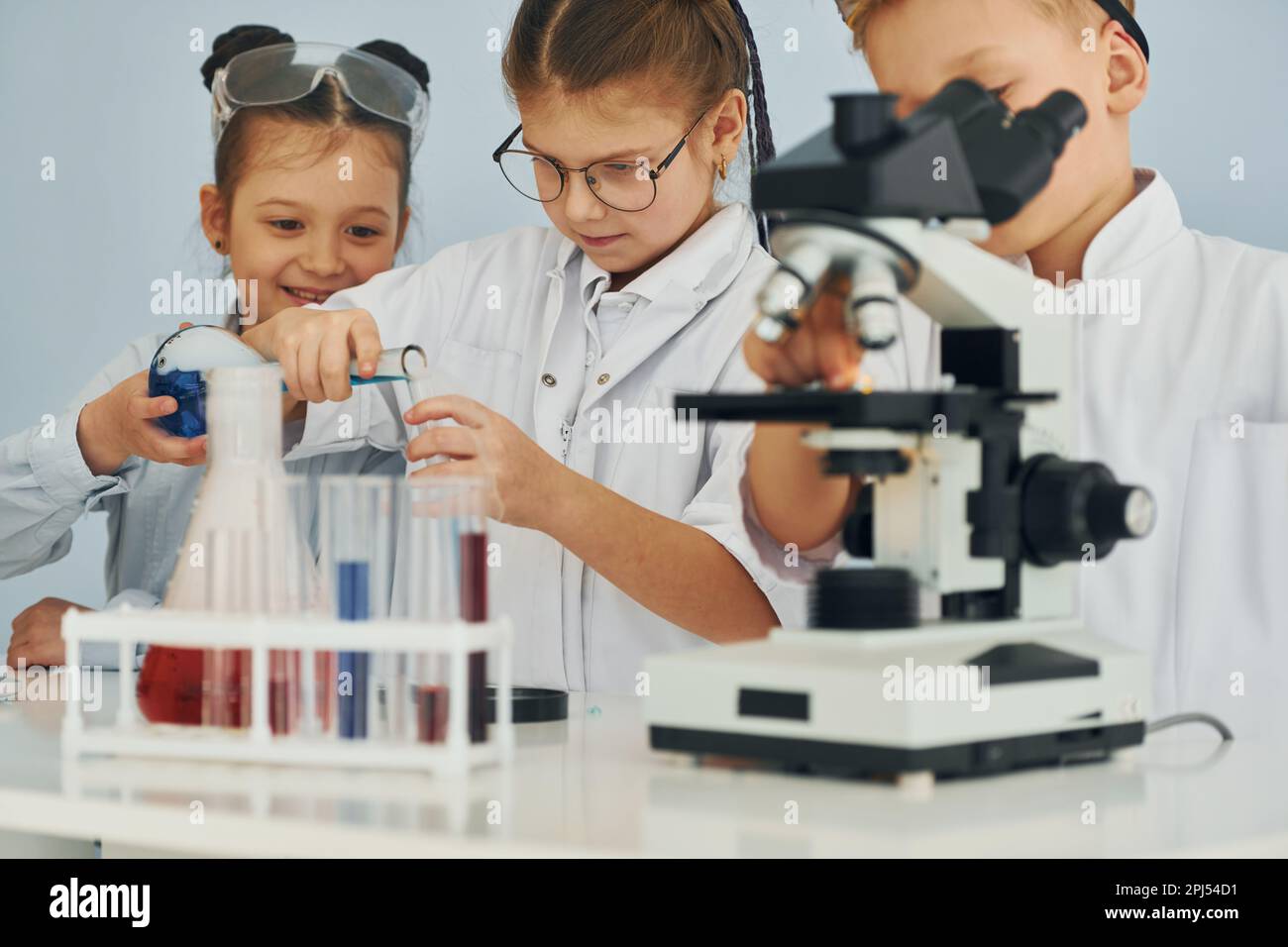 Two Young Characters With Science Club Equipment On White Background Male  And Female Teens Wearing White Coats And Smiling Set Of Scientific Items  With Microscope Science Book Tubes Formulas Stock Illustration 