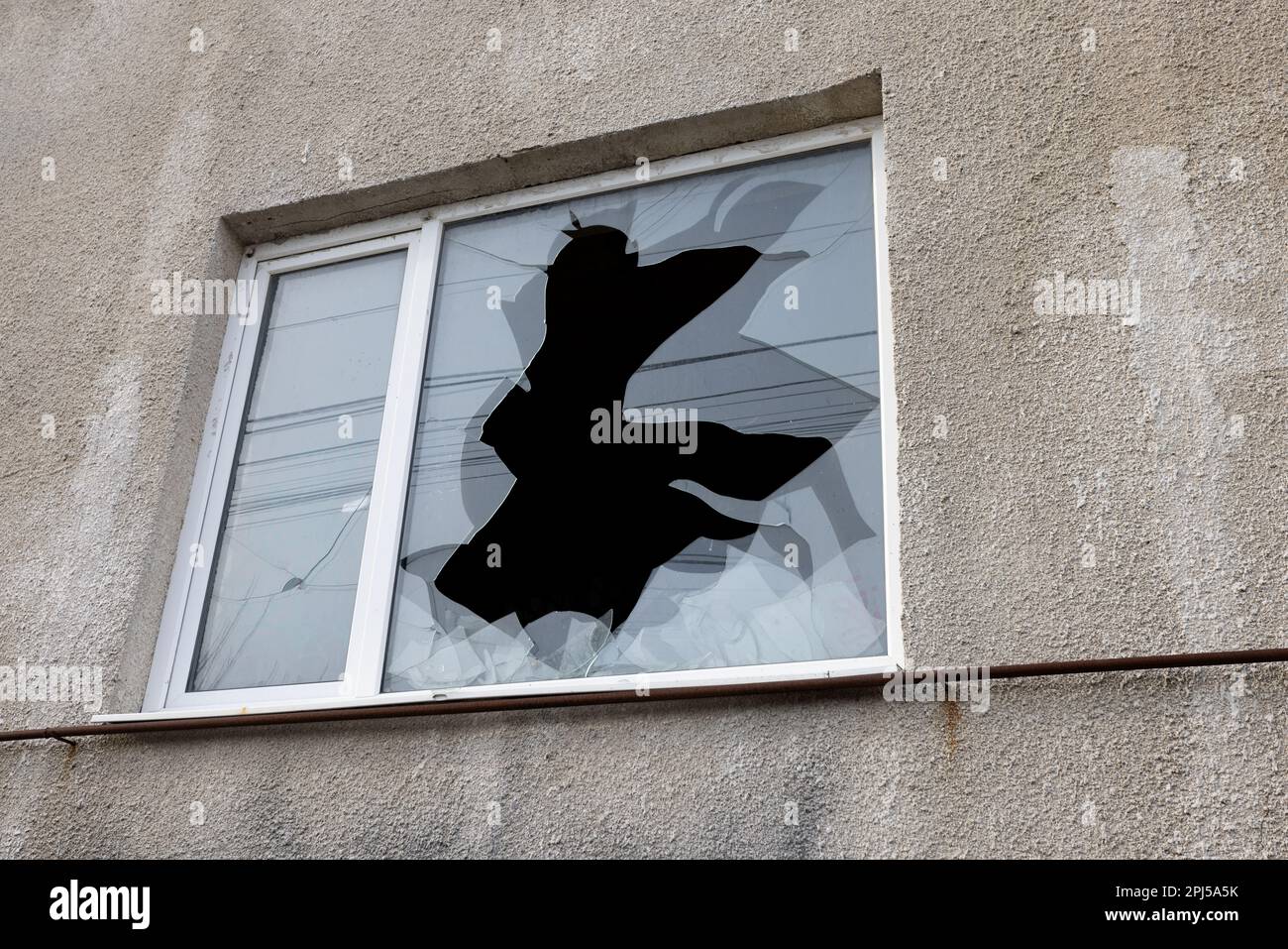bullet hole in glass is a real bullet hole of a large caliber projectile bullet. Glass door pierced by a bullet during the war, terrorist attack. Brok Stock Photo