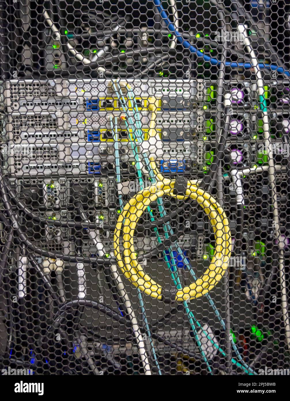 Coiled yellow cable connecting digital equipmnet installed in a rack ...