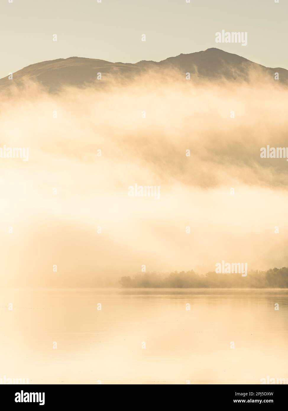 A tranquil morning scene of a misty lake reflecting the sunlit ...