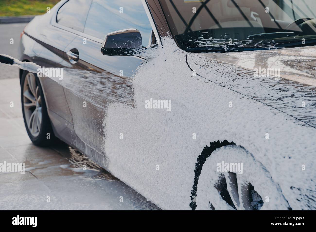 Highpressure car cleaning, worker at car wash station spraying special