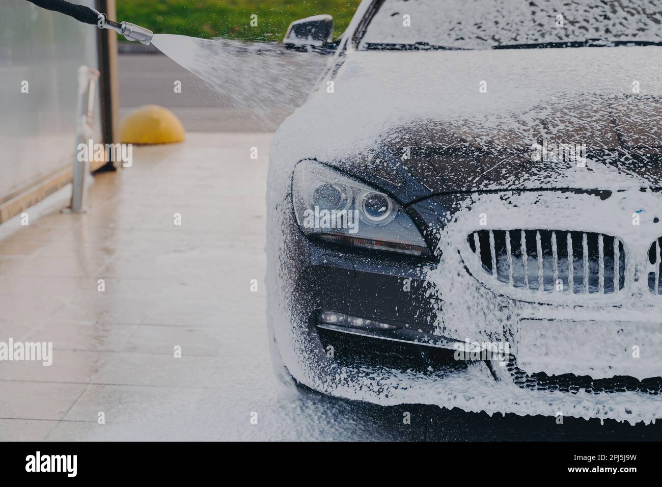 Foaming exterior of vehicle with foam gun. Outdoor vehicle washing