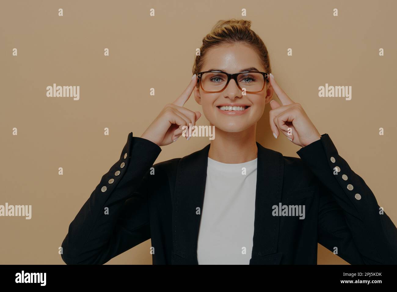 Positive blonde female student putting on eyeglasses and holding them with hands, young beautiful caucasian woman posing and looking through spectacle Stock Photo