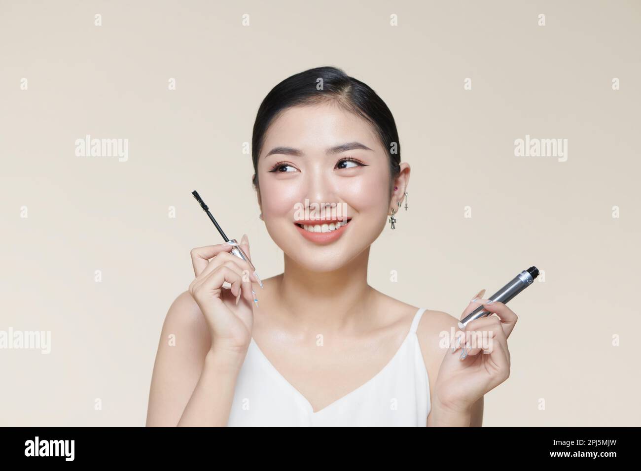 Charming young woman applying mascara. Stock Photo