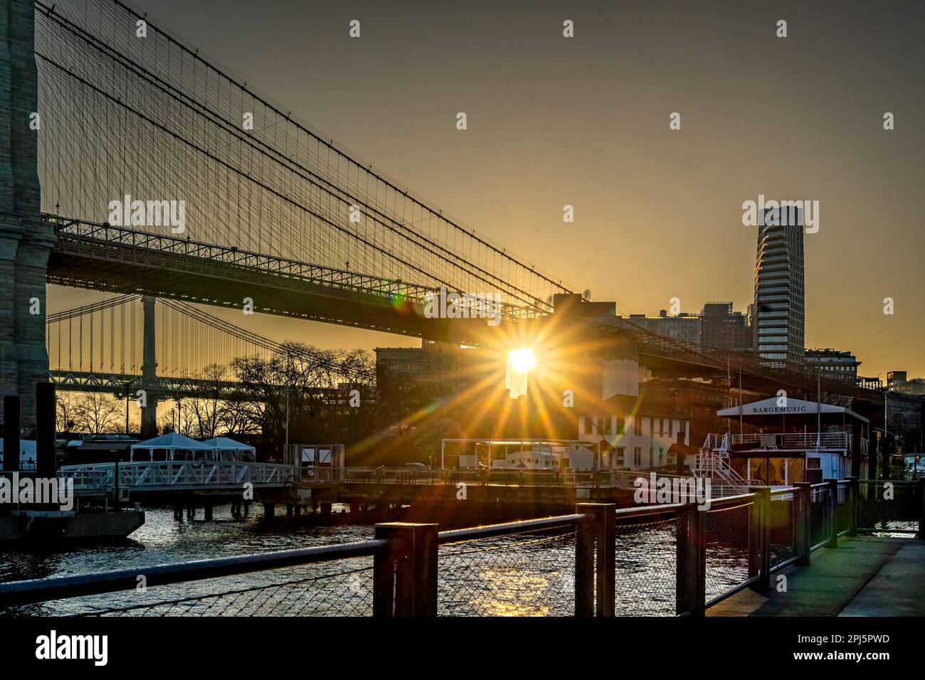 Brooklyn, NY - USA - March 26, 2023 Horizontal view of the sun rising over DUMBO section of Brooklyn and the Brooklyn Bridge. Sunrise seen from the Br Stock Photo