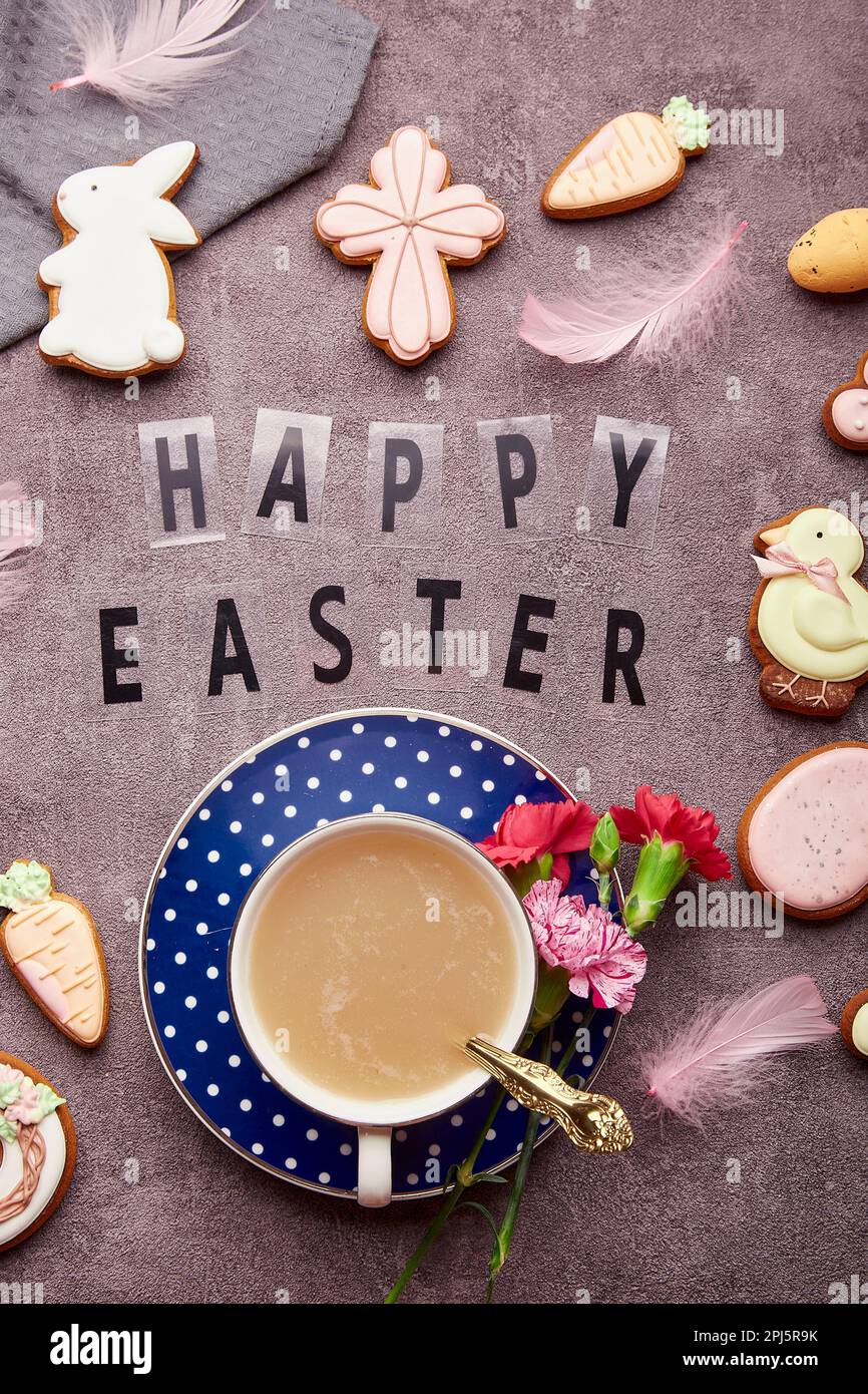 Aesthetic Easter background with text Happy Easter. Stylish decorated Easter cookies, pink flowers, coffee cup and eggs flat lay Stock Photo