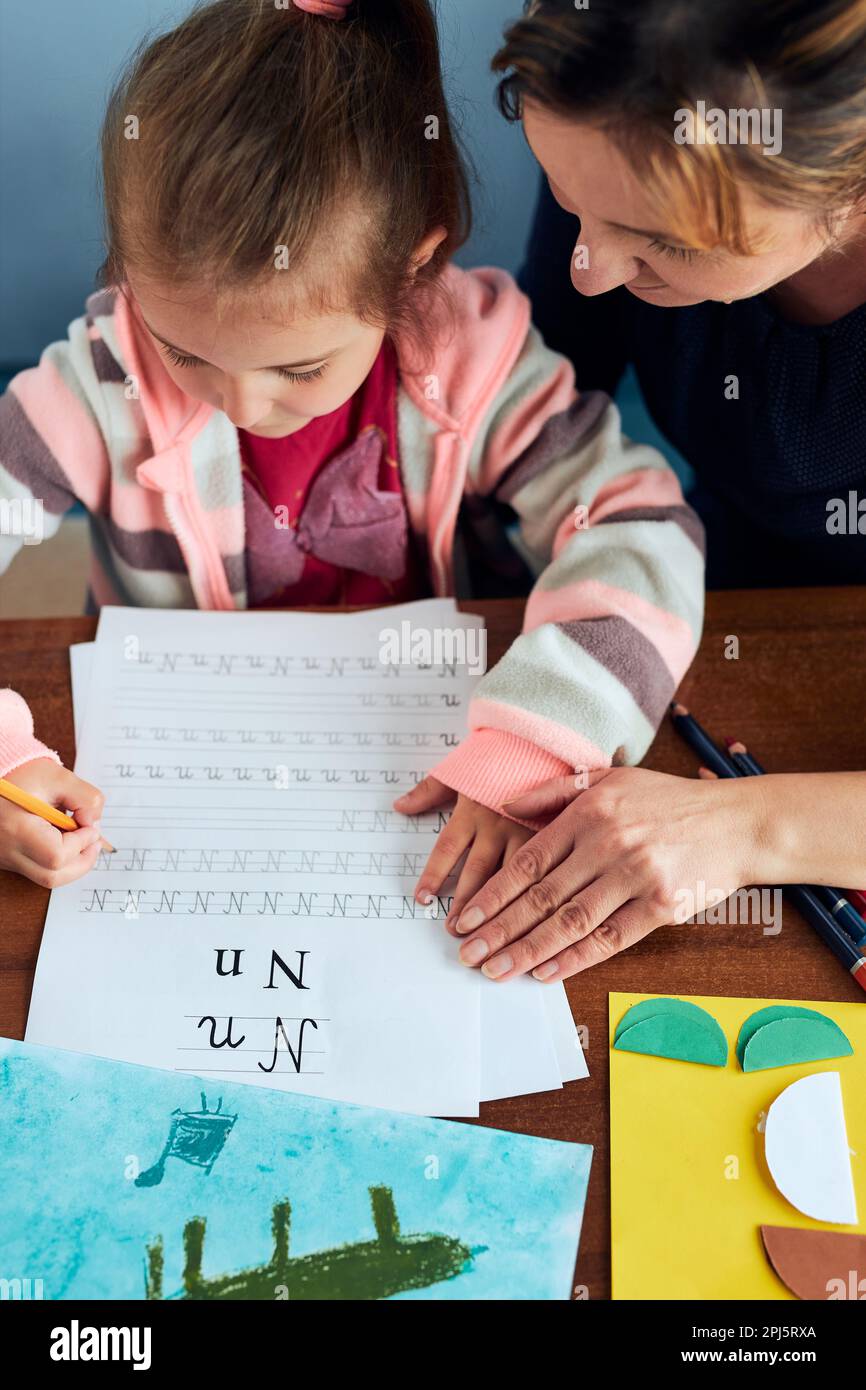 Little girl preschooler learning to write letters with help of her