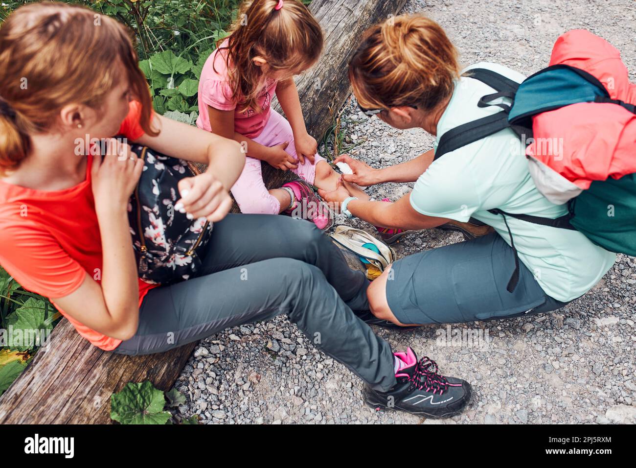 Mother dressing the wound on her little daughter's knee with medicine