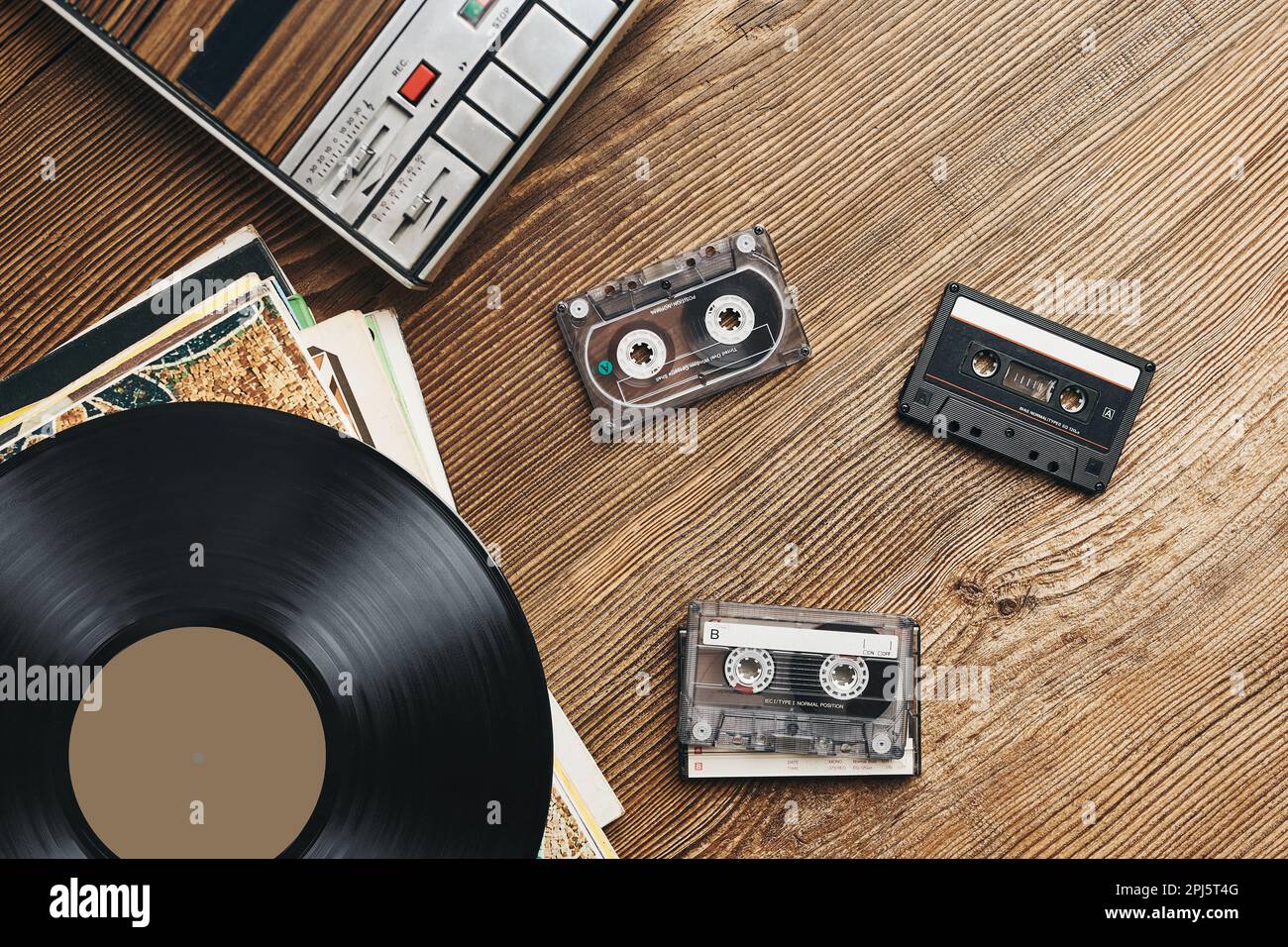 Vinyl records, cassette tapes and cassette recorder on wooden table
