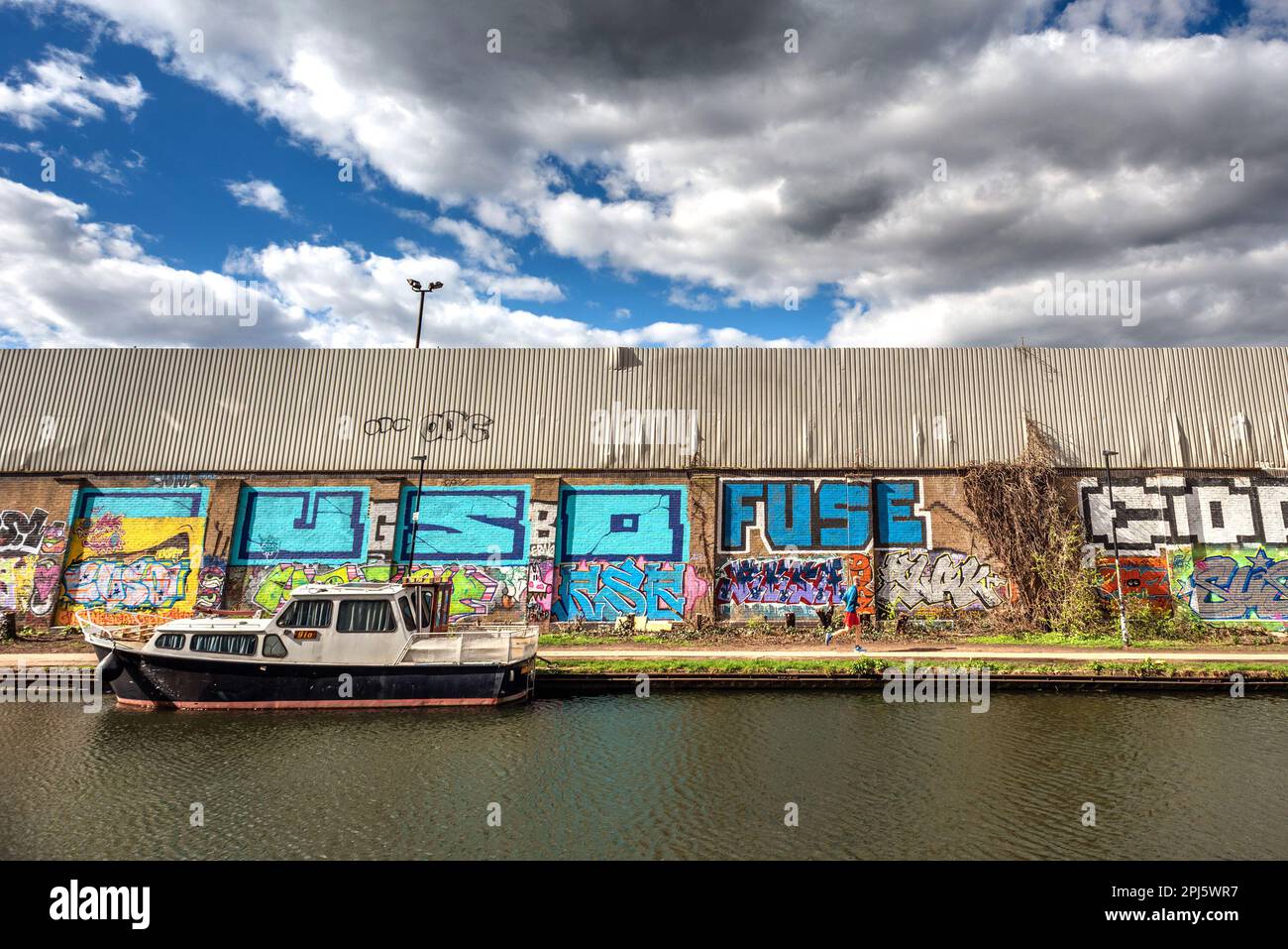 London, March 27th 2023: A jogger running alongside the Hertford Union Canal in Tower Hamlets, London Stock Photo
