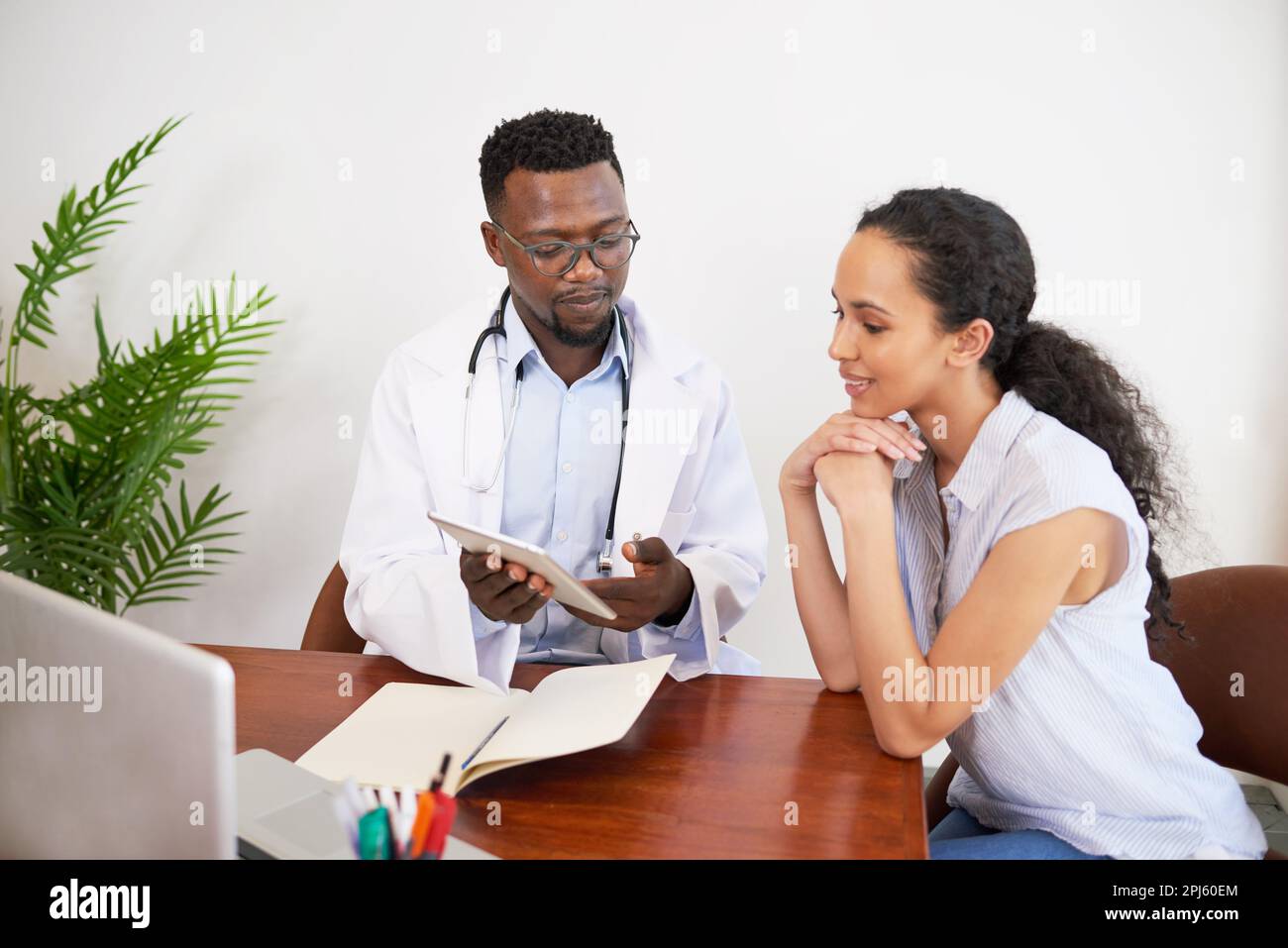 Black male doctor and female patient discuss labwork results at doctor ...
