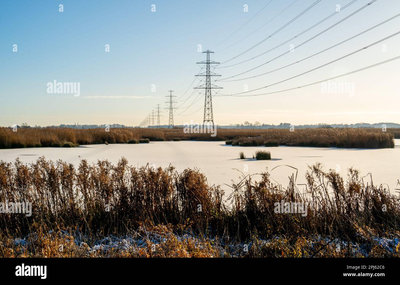 Winter landscape with frozen lake and row of power pylons Stock Photo ...
