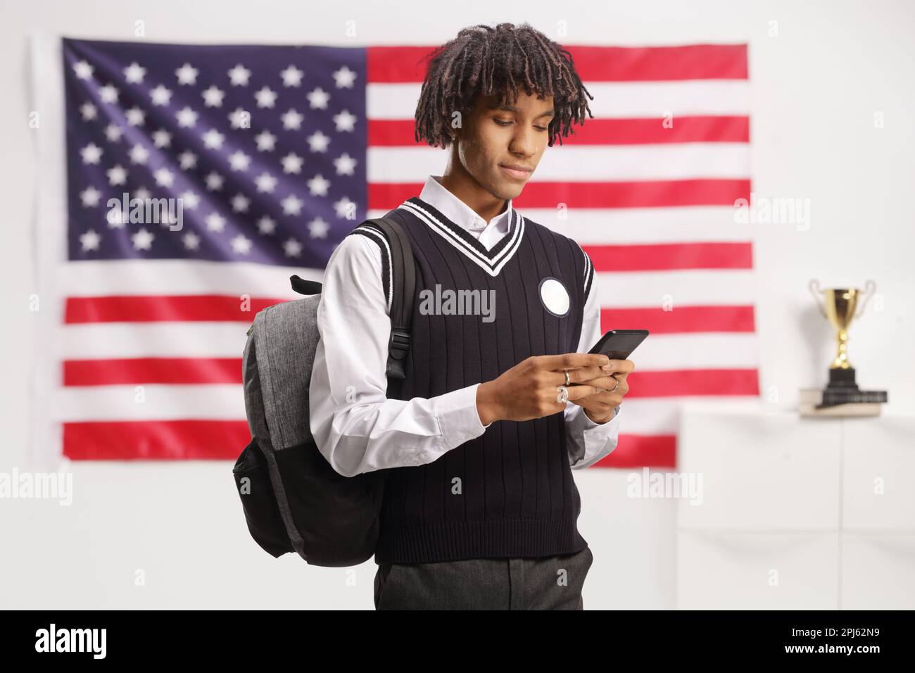 African american male student in a uniform using a smartphone in front ...