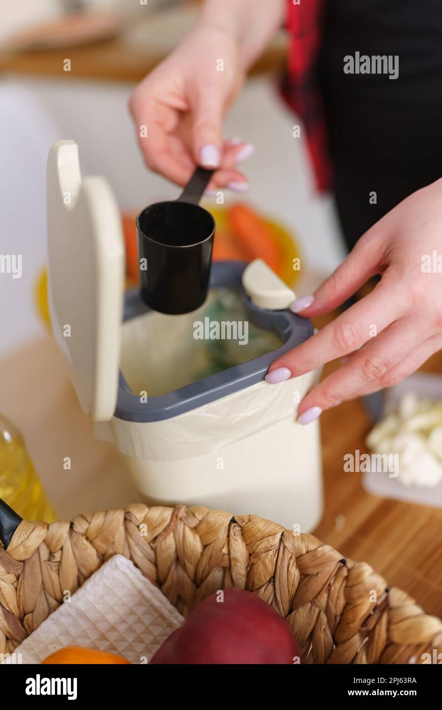 Female hand put bokashi bran in a compost container for fermentation