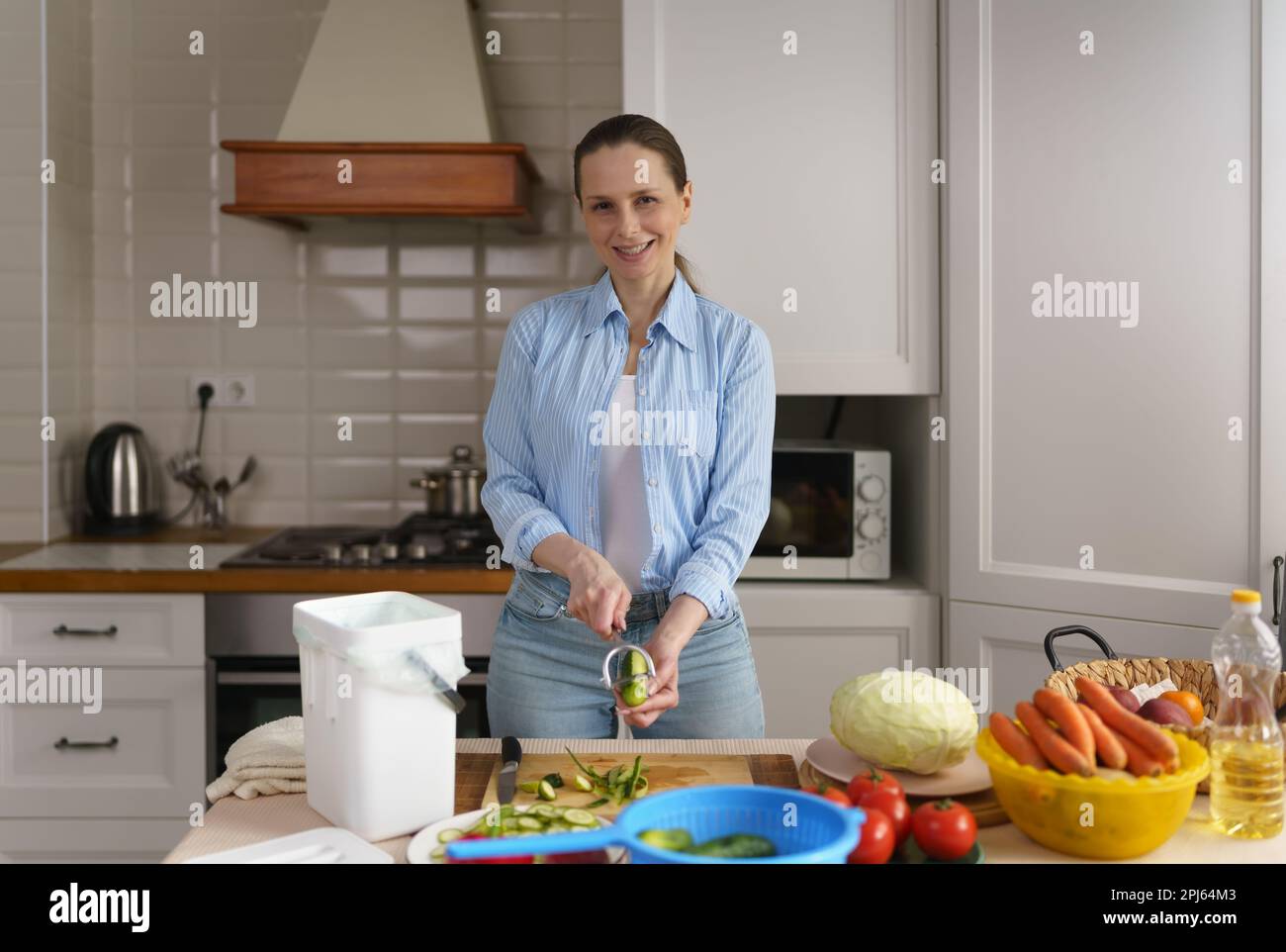https://c8.alamy.com/comp/2PJ64M3/happy-adult-woman-peeling-off-cucumbers-for-lunch-and-composting-organic-food-waste-in-a-compost-bin-2PJ64M3.jpg