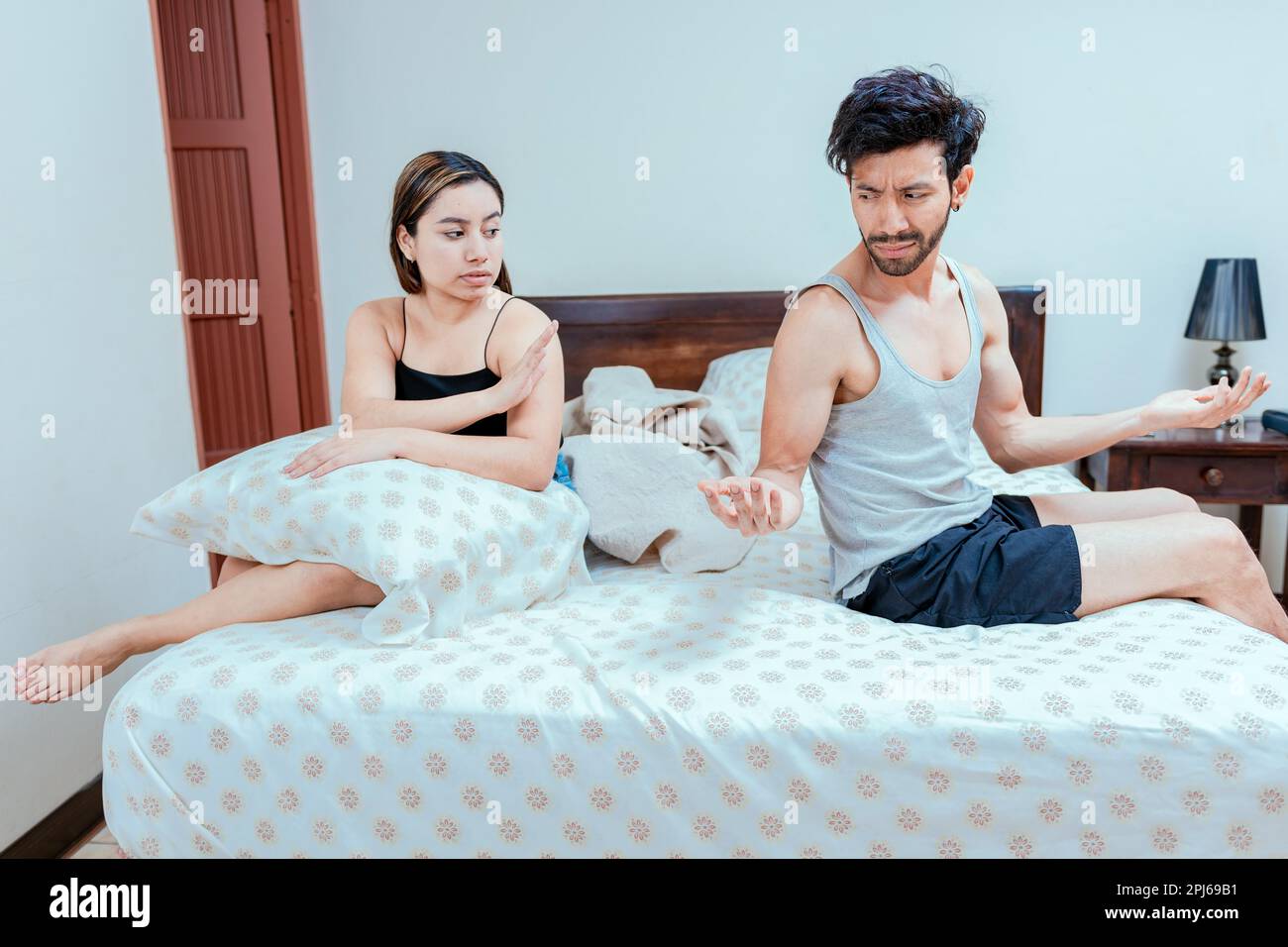 Man arguing with his wife in the bedroom bed. Upset wife ignoring husband in bed. young couple arguing in the bedroom. Concept of couple crisis in bed Stock Photo