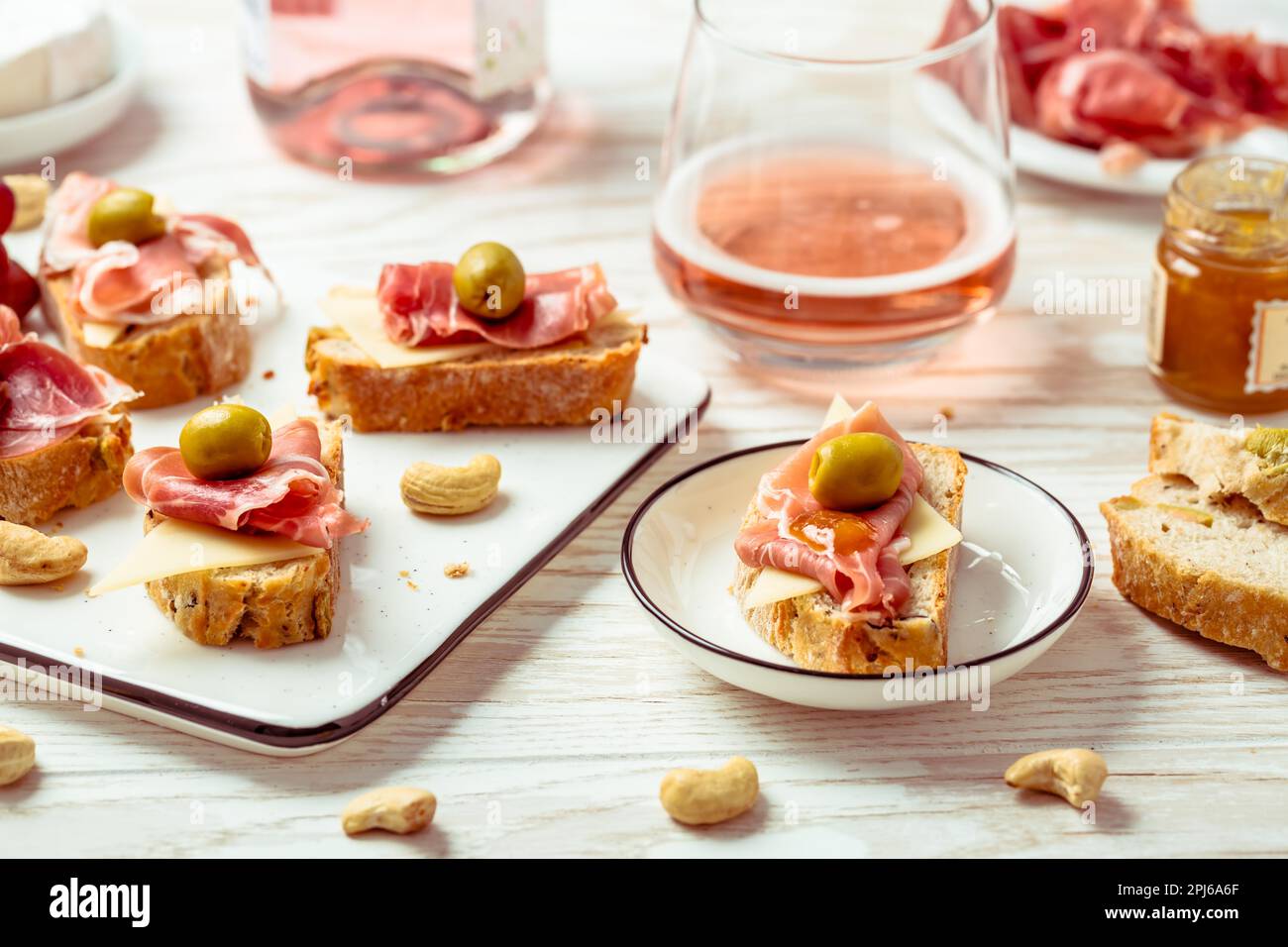 Appetizers and open sandwiches with Italian antipasti, camembert, Parma ham and rose wine on wooden table Stock Photo
