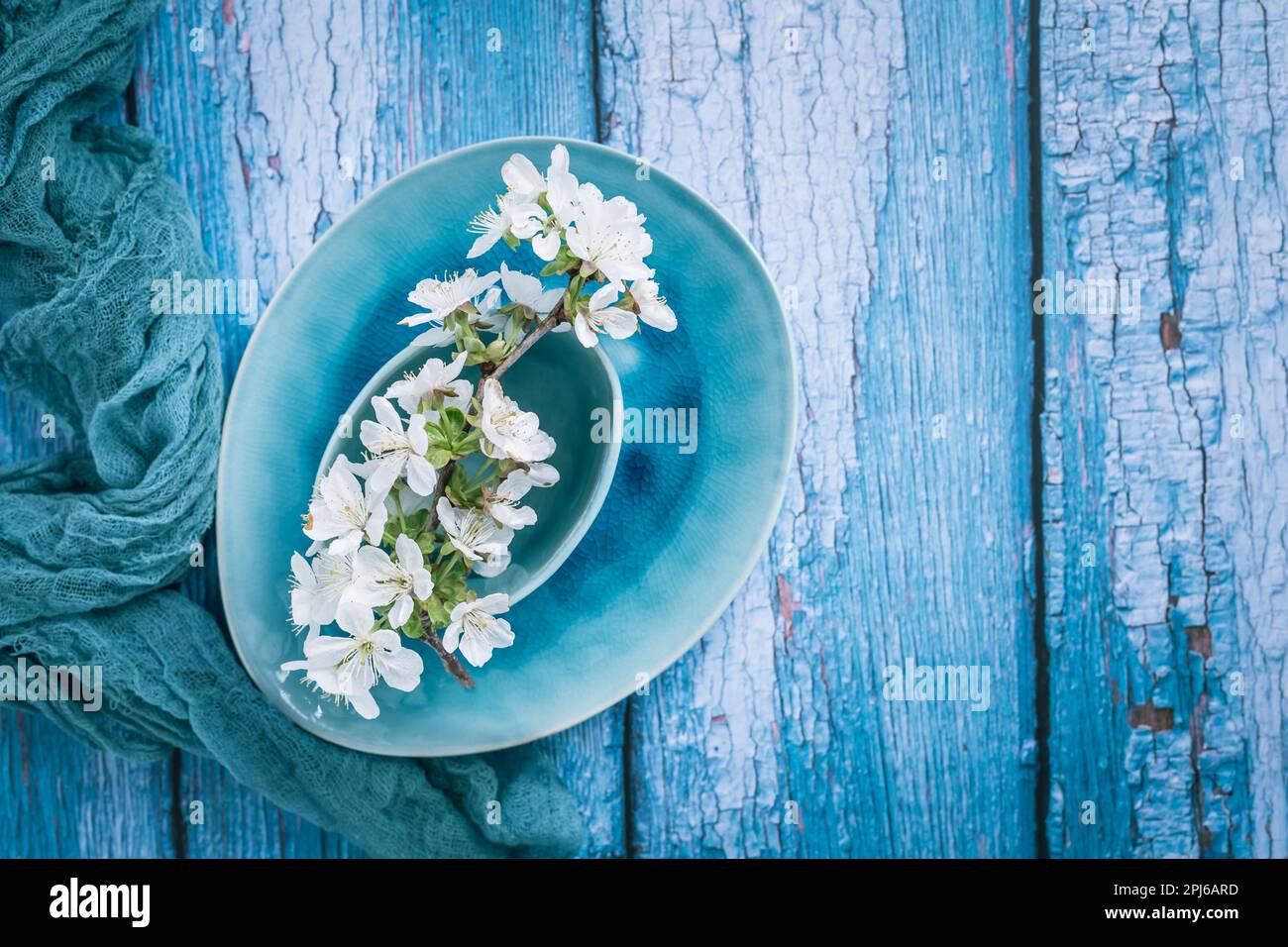Pottery bowls or ceramics in green and blue tone with blooming cherry branch. Kitchenware Stock Photo