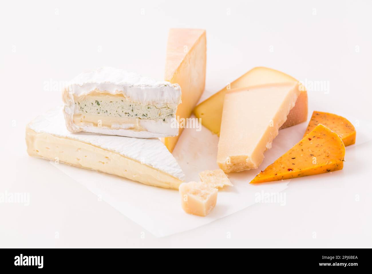 Assortment of different cheeses on white background. Hard cheese, parmesan, brie and chili cheese Stock Photo