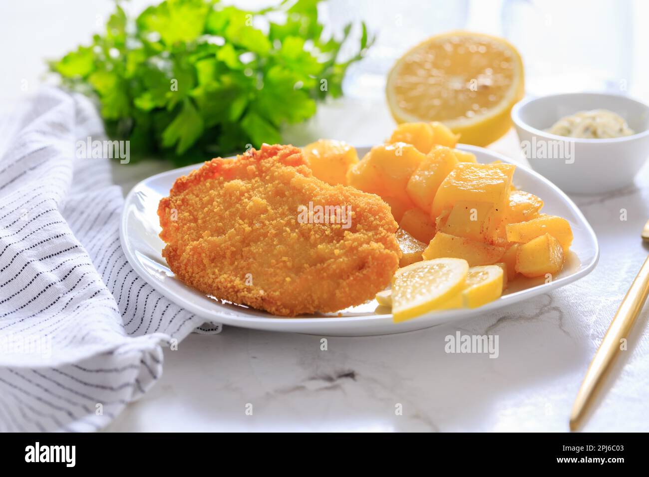 Homemade chicken escalope with baked potatoes, mayonnaise and lemon Stock Photo