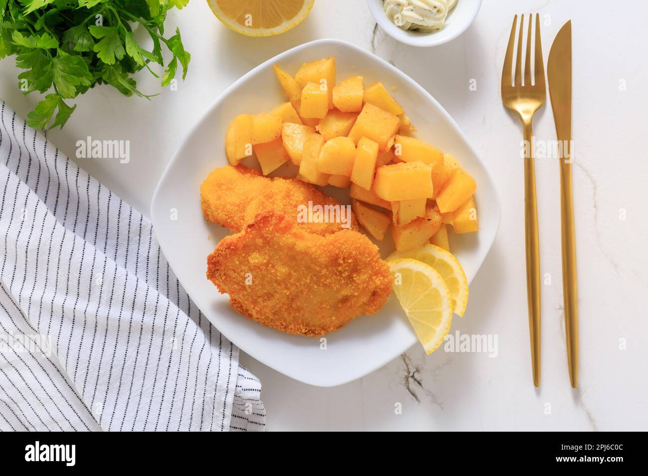 Homemade chicken escalope with baked potatoes, mayonnaise and lemon Stock Photo